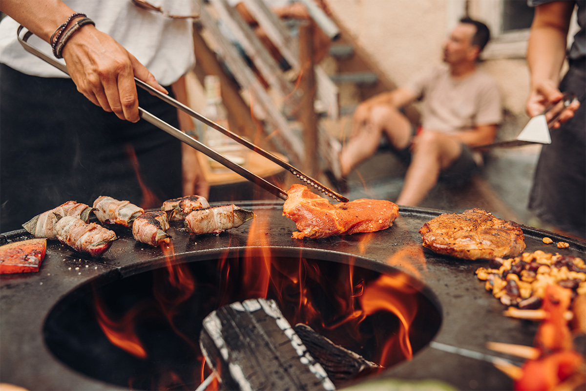 Feuerzange Abgebildet ist eine Person, die Essen auf einem Grill zubereitet, mit den Grillzangen.