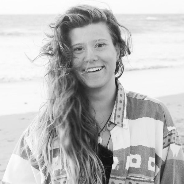 Eine Frau sitzt am Strand, während ihr Haar im Wind weht.