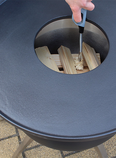 Scène montrant une personne allumant un morceau de bois dans un brasero