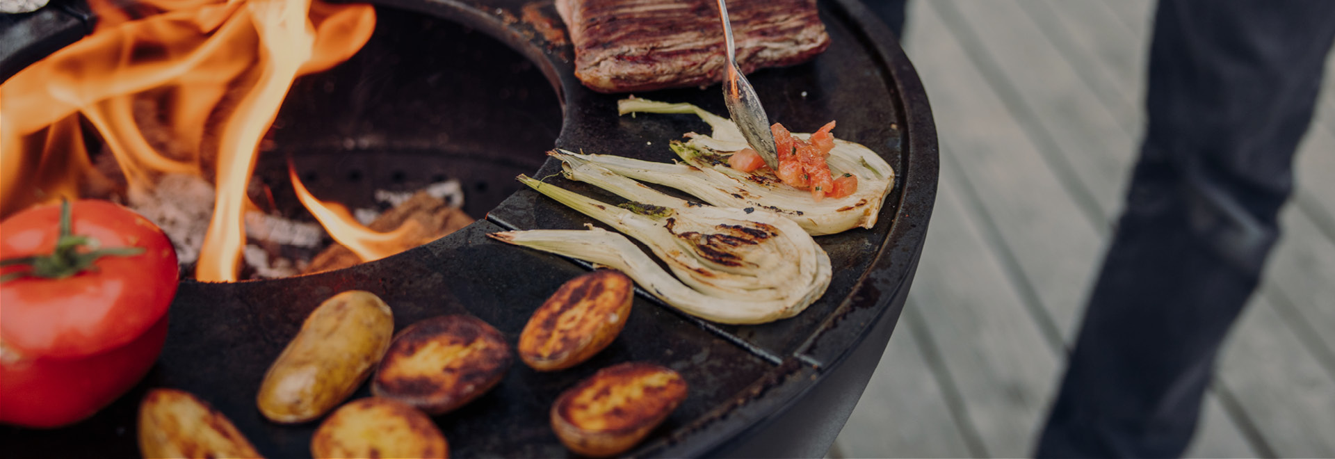 An image showing a person is cooking food on a grill, with the CUBE Plancha.