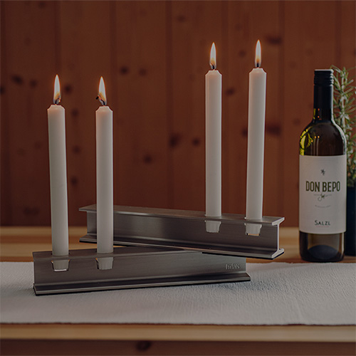 A bottle of wine and candles on a table,showing examples for product customisation with the henry metal candleholder