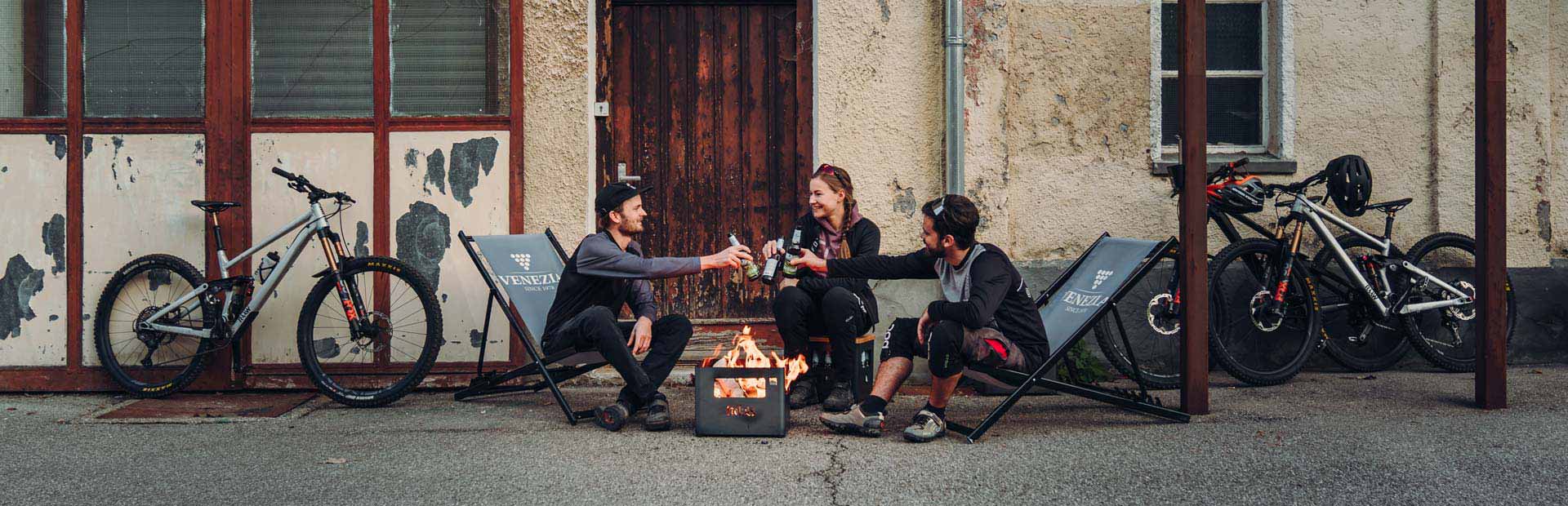Ici sont représentées deux personnes assises autour d'un brasero, avec le Brasero BEER BOX.