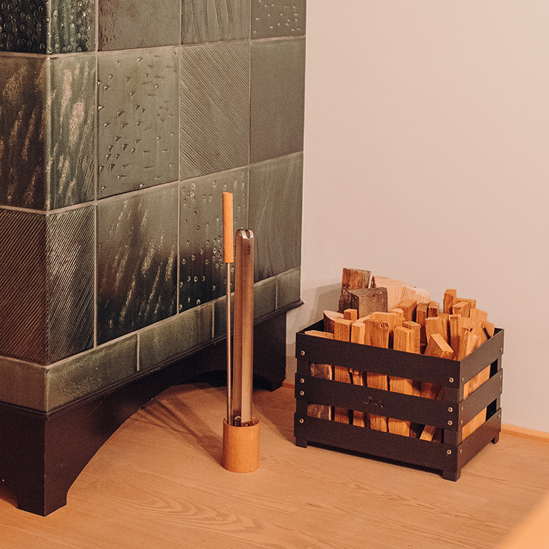 Een afbeelding van een open haard met brandhout en een houten houder.