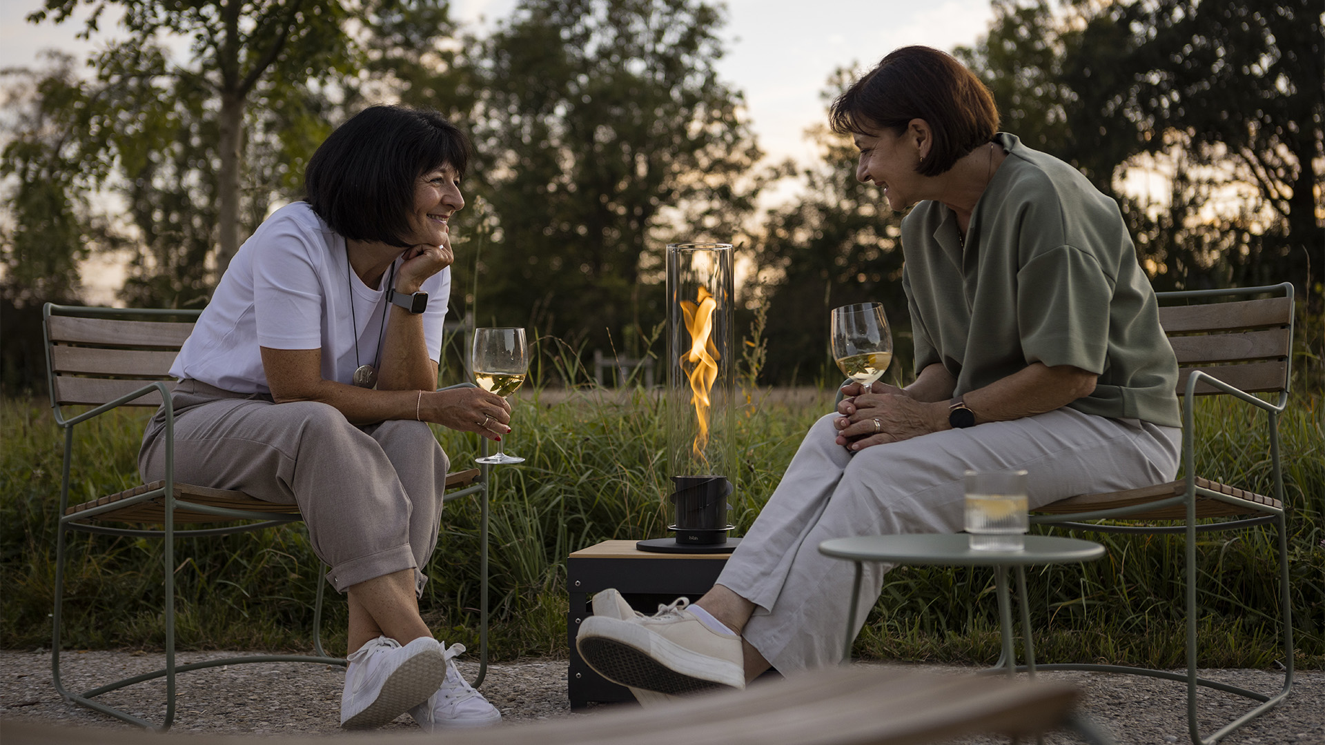 The 00700 Spin 1200 Tablefire black is shown as two women sitting on a bench with wine glasses, creating a stylish and accessible visual.