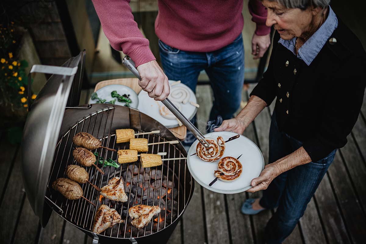 CONE Charcoal Grill Depicted here is a man and woman grilling food on a grill, with the CONE Charcoal Grill.