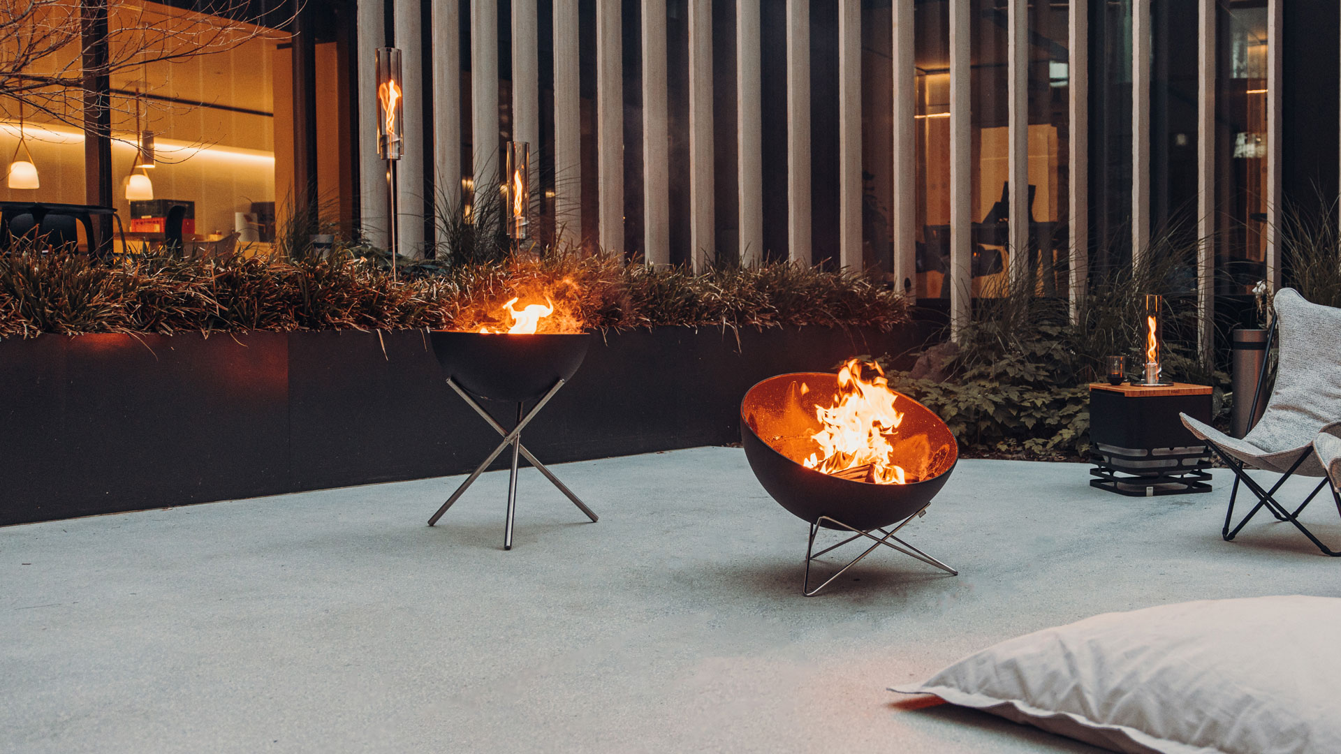 Een uitzicht op een vuurplaats in een kamer met een bed en een stoel, met de BOWL Fire Set Flex.