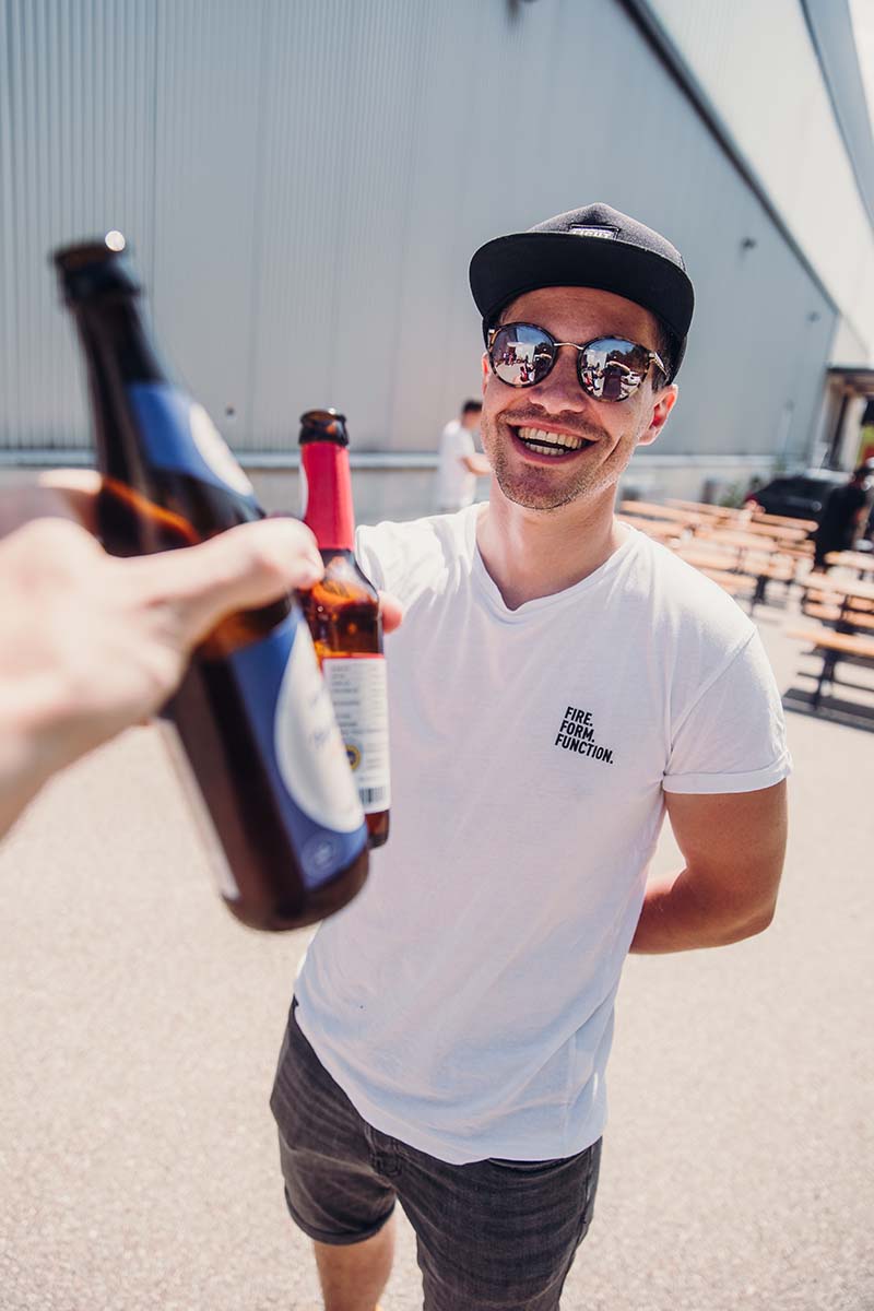 a man holding a beer bottle and smiling.