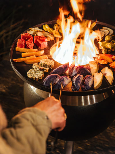 De 00861 Moon 45 Plancha integreert naadloos in de omgeving, waar een persoon voedsel aan het grillen is met een tang.