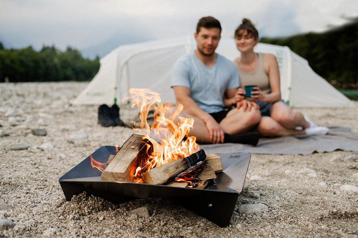 TRIPLE 65 Fire Bowl Experience a man and woman sitting next to a campfire with the refined touch of the Triple 65 Fireplace