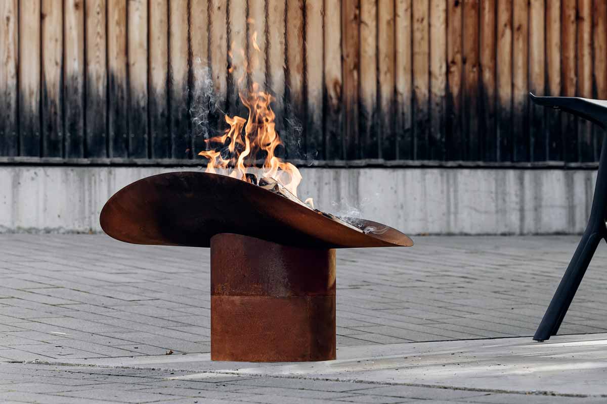 ELLIPSE Pied Ici est représenté un brasero avec une chaise et une table, avec le bol à feu ELLIPSE.