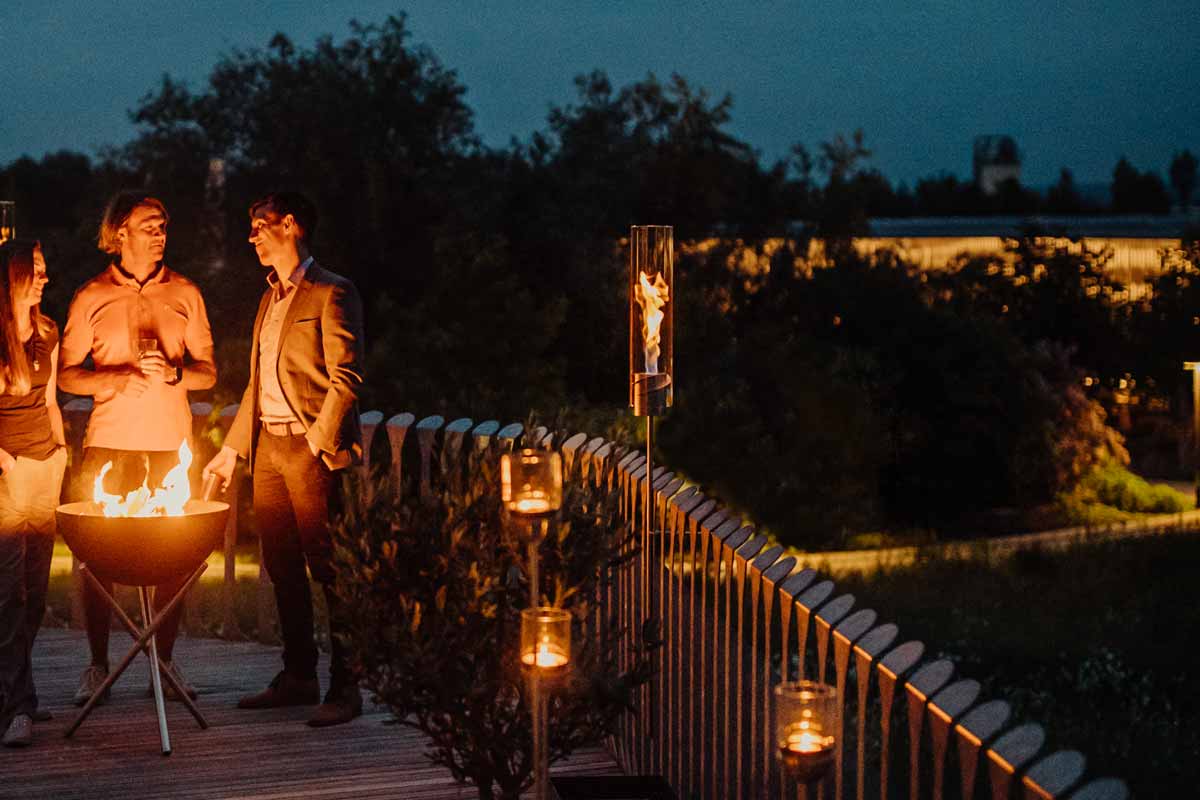 SPIN Ground Spike silver a couple standing on a deck next to a fire