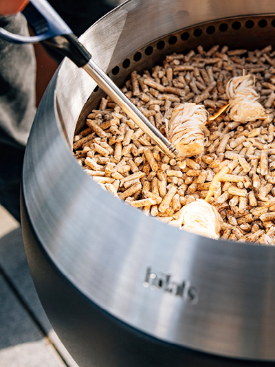 A person is lighting up wooden chips into a fire basket. Showing how to light the MOON 45