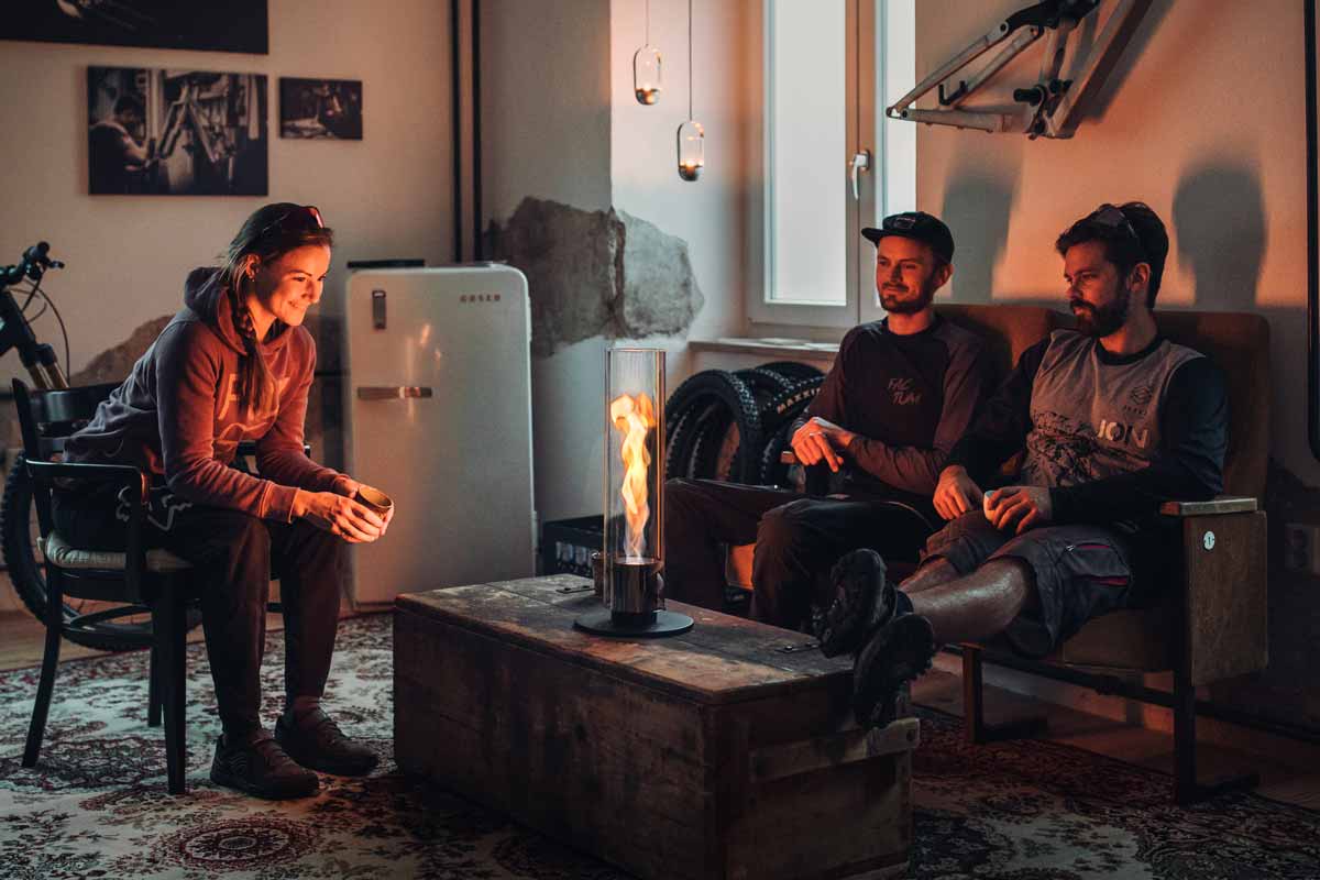 Bioethanol Gel Fuel 1l Bottle | 6-pack Illustrated is two people sitting in a living room with a fire, with the Bioethanol Liquid Fuel 1l Bottle | Six-Pack.