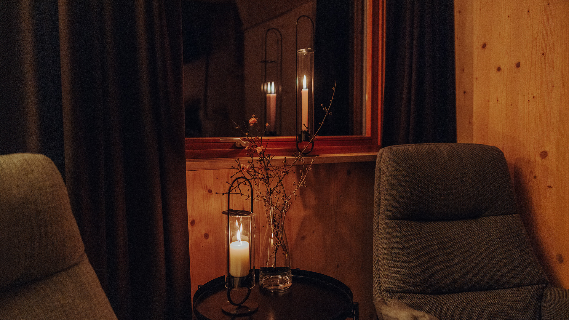 Een afbeelding van een stoel en een tafel met een kaars erop, waarbij de 00273 Ovale Kaars 35 zwart als centraal en doelgericht element wordt getoond.