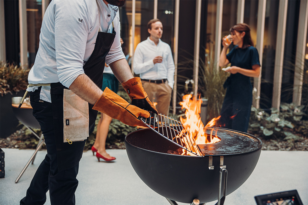 BOWL 70 Grille Cette image montre un homme en train de cuisiner sur un grill, avec la Grille BOWL 70.