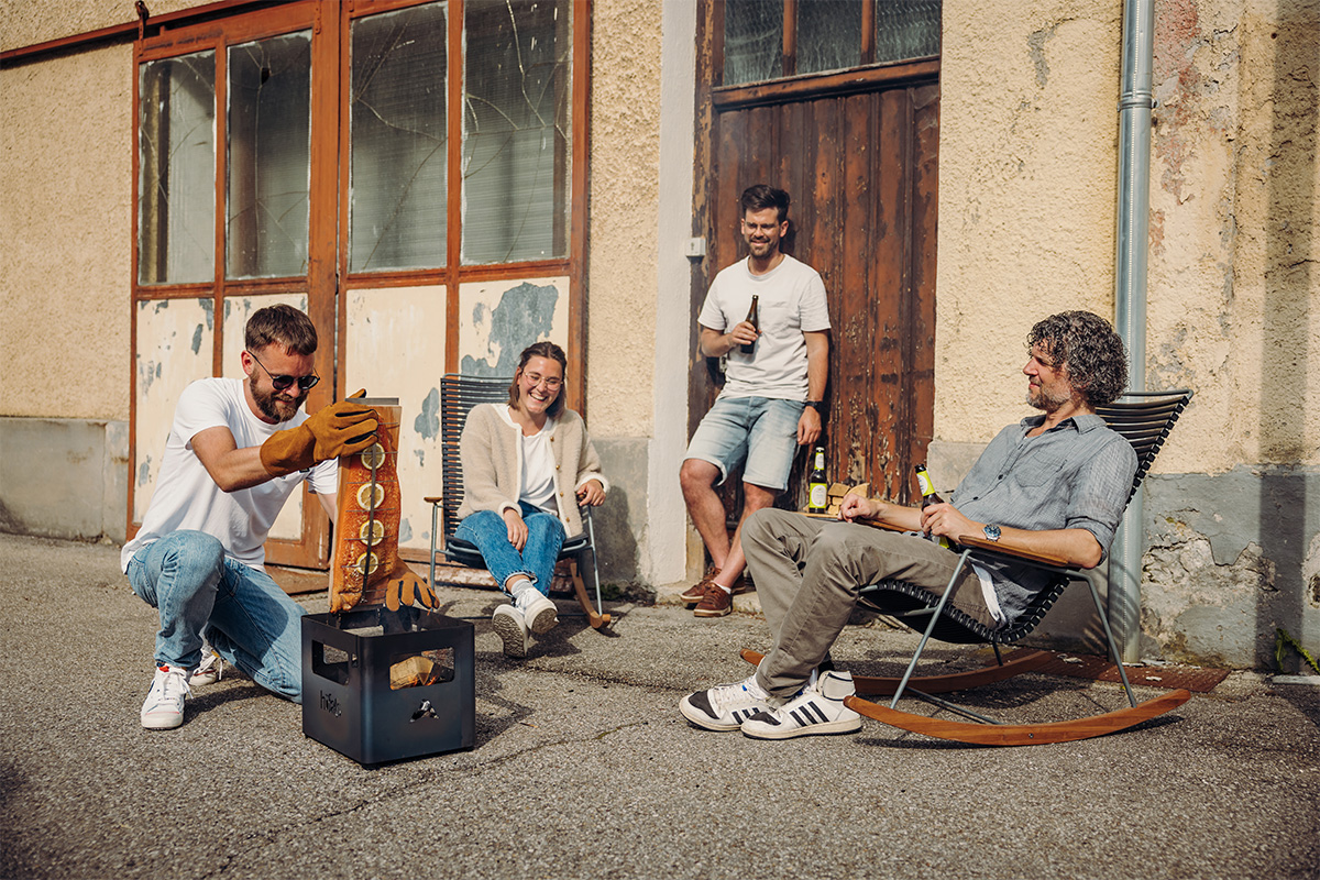 Flammlachs-Brett Dargestellt ist eine Gruppe von Menschen, die auf einem Bürgersteig sitzen, mit dem Flame-grilled Lachs-Brett.