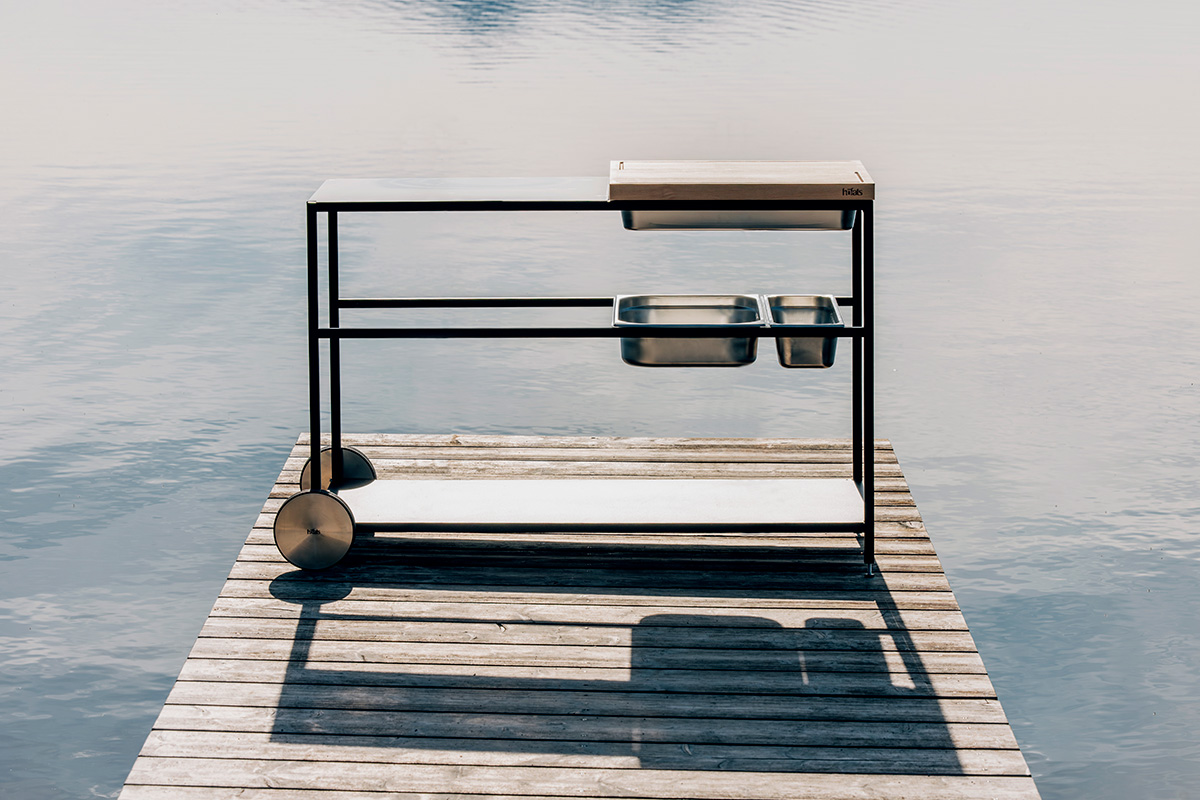 Hier ist eine Bowl auf einem Metallgestell auf einem Steg im Wasser abgebildet, mit der FIRE KITCHEN Outdoor-Küche.