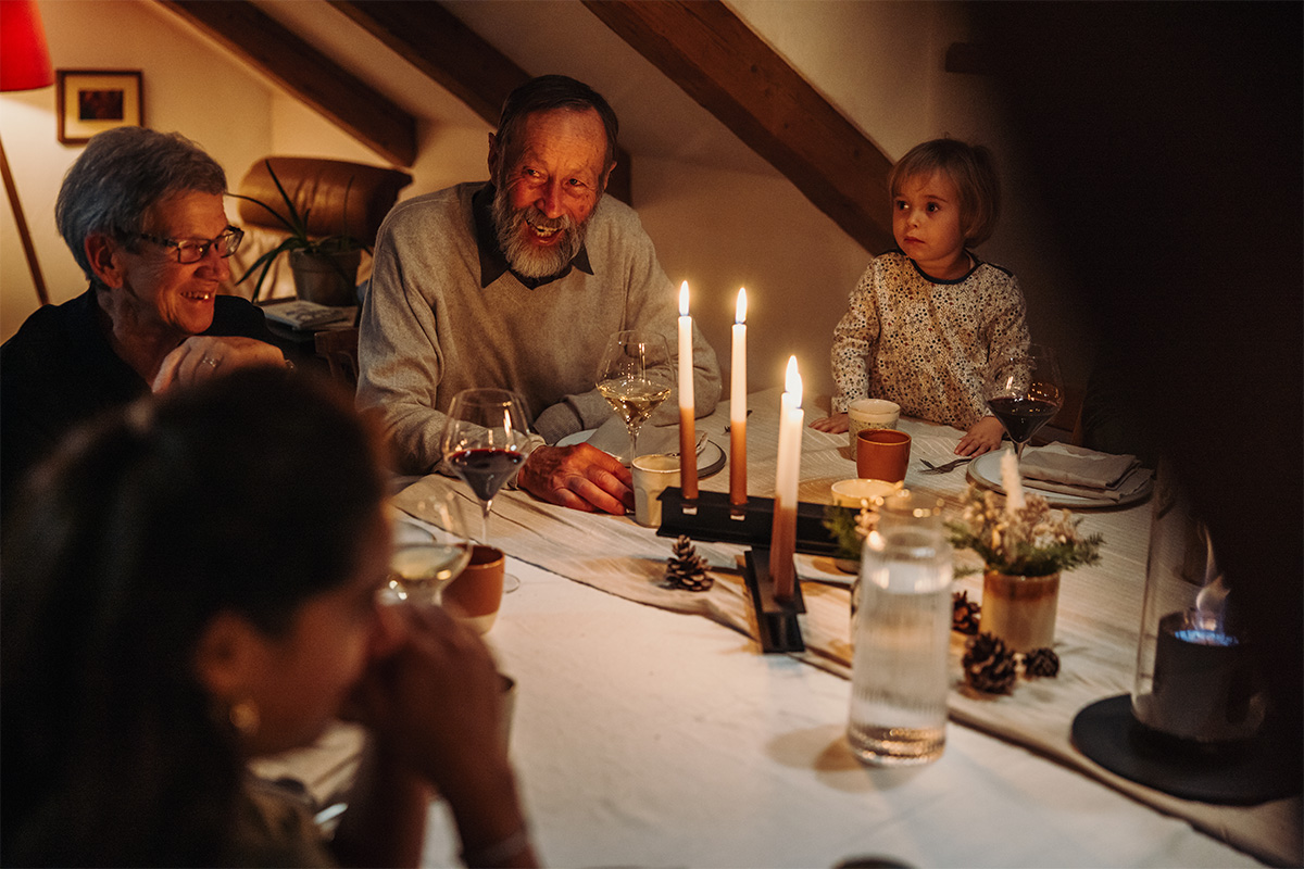 HENRY METAL II Bougeoir noir Une famille assise à une table avec des bougies dessus, avec le 00663 HENRY METAL II noir ajoutant une touche fonctionnelle et élégante à la scène.