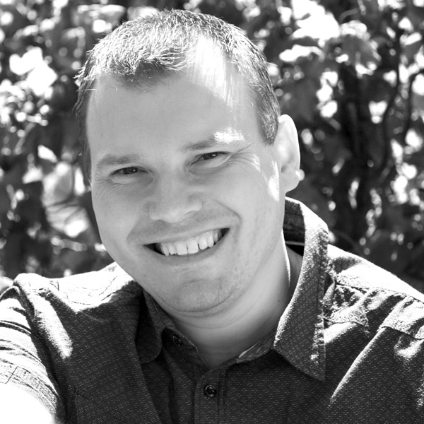 Ein Mann lächelt, während er im Park sitzt.