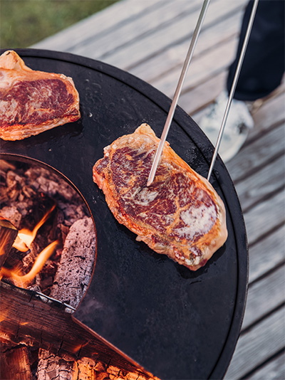 An image showing a grill with meat, with the CUBE Plancha.