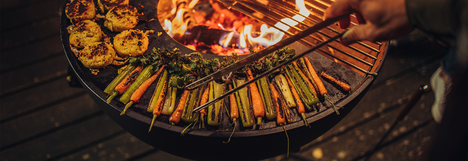 De Bowl 70 wordt getoond terwijl iemand eten op een grill aan het bereiden is, wat een stijlvol en toegankelijk beeld creëert.