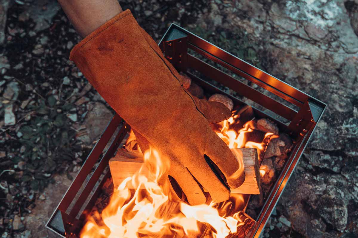Gants ignifuges en cuir Une image montrant une personne tenant un feu dans une boîte en métal.