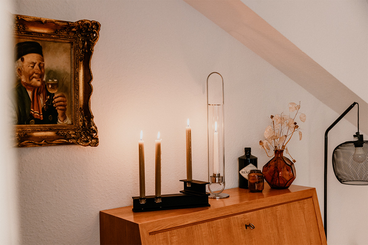 OVAL CANDLE 55 Bougeoir argent Une photo d'un homme sur un mur, enrichie par la présence de la OVAL CANDLE 00271, qui allie design et utilité.