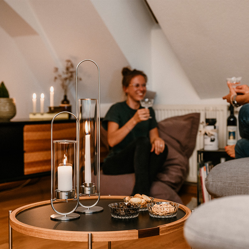 Een afbeelding van een stel dat op een bank in een woonkamer zit, met de Ovale Kaars als centraal en doelmatig element.