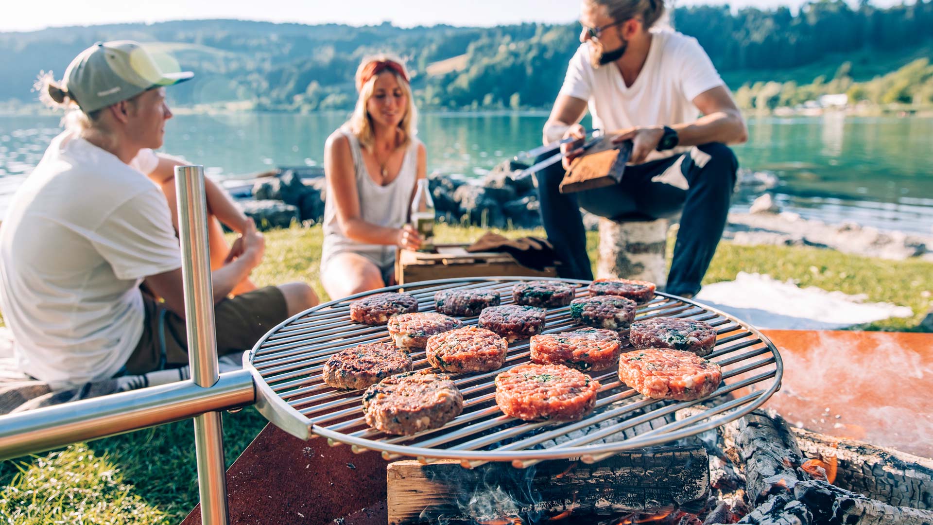 Een afbeelding van een man en een vrouw die vlees grillen op een barbecue, waarbij de Triple 90 Openhaard BBQ-set als centraal en doelgericht element wordt weergegeven.