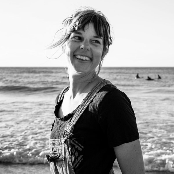 Eine Frau steht am Strand, ihr Haar weht im Wind.