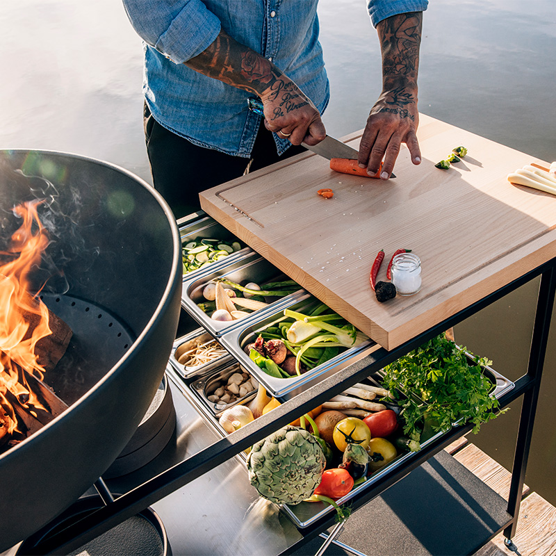 This image shows a man cooking on a grill, with the FIRE KITCHEN.