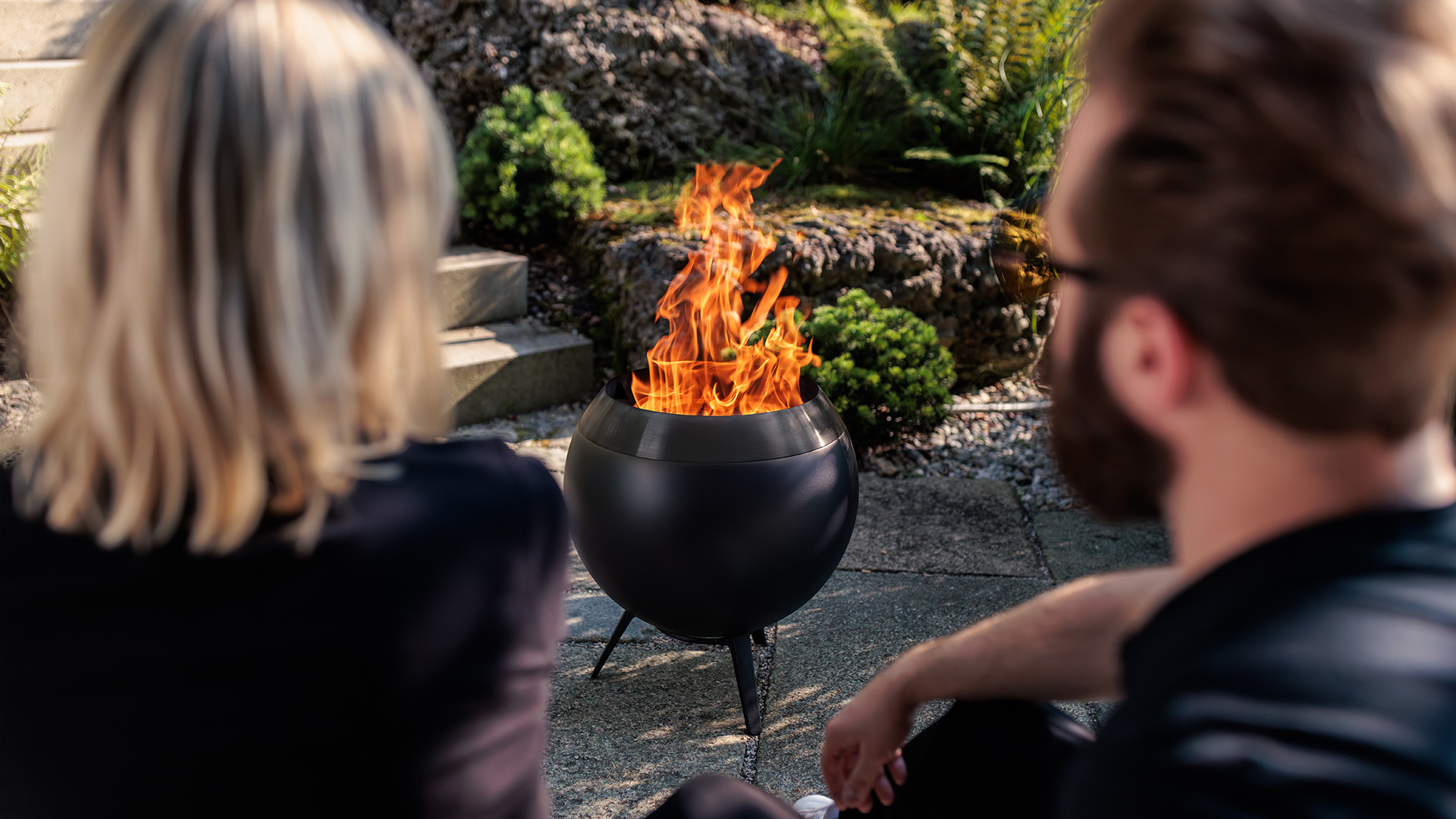 Zwei Personen schauen in die lodernde Flamme von MOON mit niedrigem Fuß. Zu sehen sind deren Hinterköpfe.