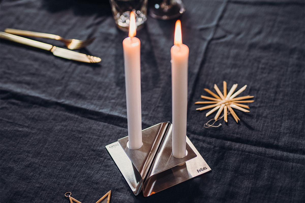 SQUARE CANDLE Bougeoir argent Une image montrant une bougie et une serviette sur une table, avec le porte-bougie SQUARE CANDLE en argent.