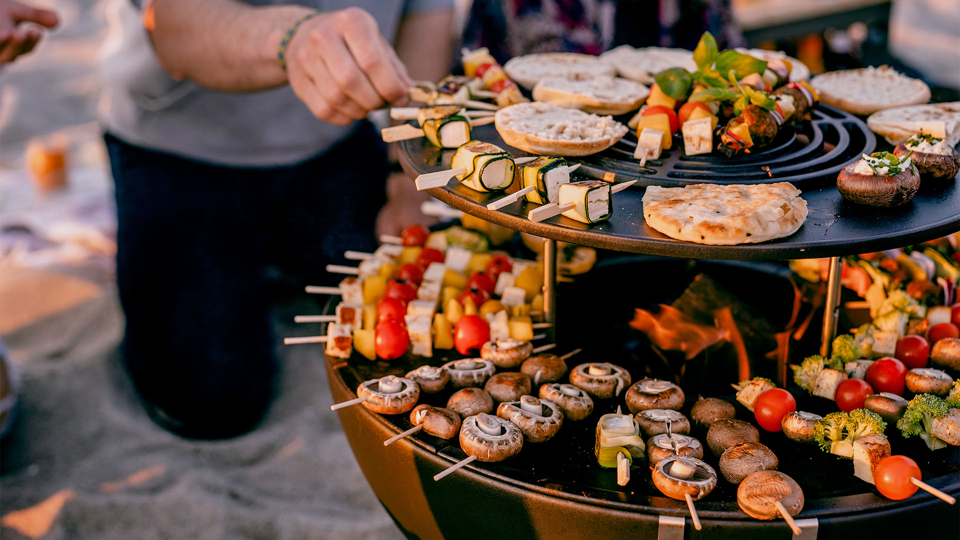 A depiction of a table with a variety of food on it, featuring the 00613 Bowl 57 Sear Grate Warming Ring as a central and purposeful element.