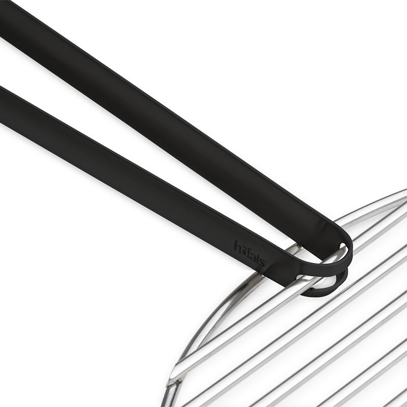 Die 00859 Grillzange wird als schwarze Metallzange dargestellt, die an einem Stahlrost befestigt ist und so ein stilvolles und zugängliches Bild erzeugt.