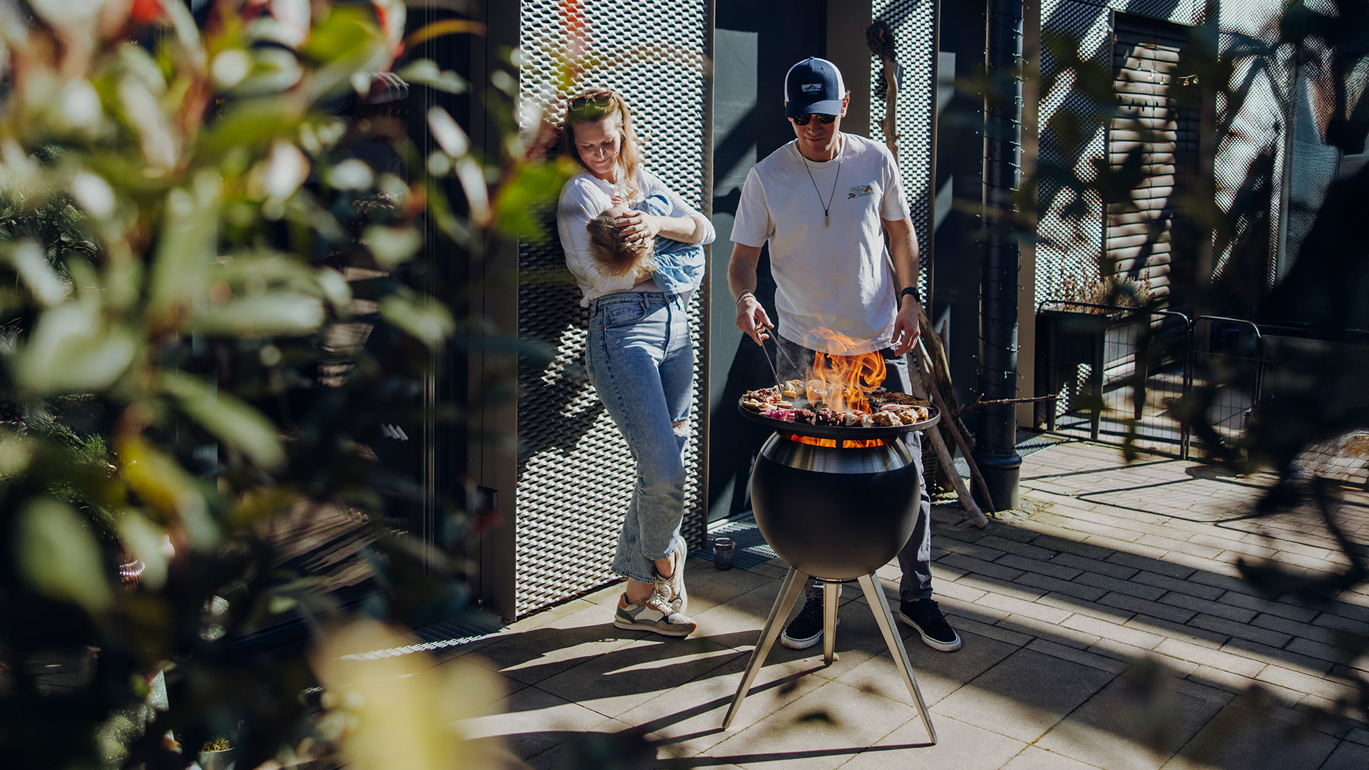 A depiction of a man and woman are cooking on a grill, featuring the 00963 Moon 45 Plancha BBQ Set high as a central and purposeful element.