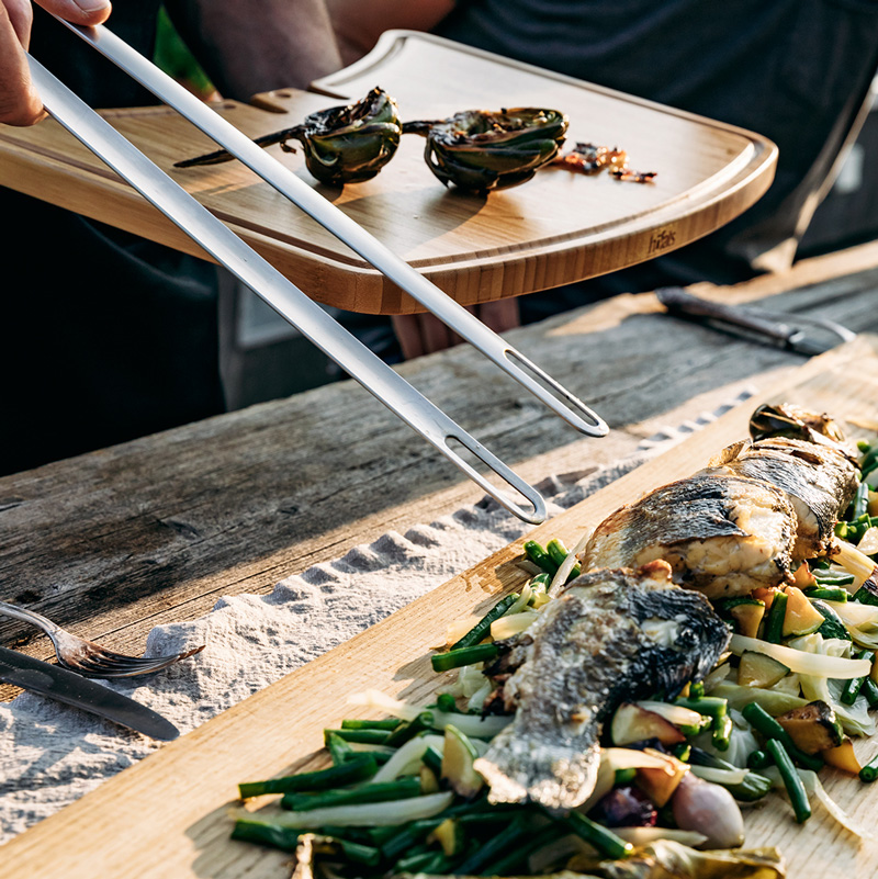 This image shows a person cutting fish on a wooden cutting board
