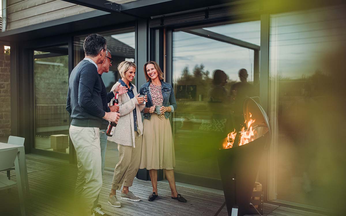 An image showing a couple standing on a deck next to a fire