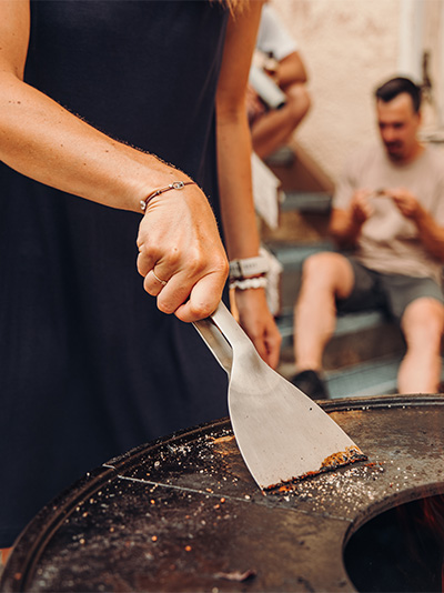A view of a man cutting a piece of meat on a grill, with the CUBE Plancha.