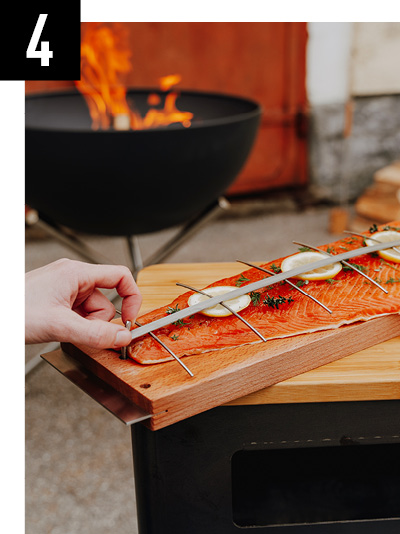 a person is cutting a piece of salmon on a wooden board.