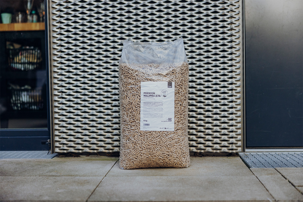 Premium Holzpellets 2x15kg Set Das Produktbild zeigt die 01003 Premium Holzpellets in einem Beutel, der auf dem Bürgersteig steht und ein stilvolles und zugängliches Bild erzeugt.