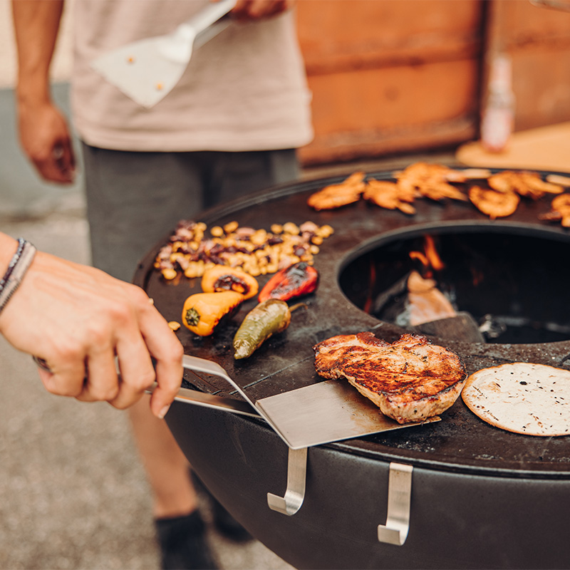 Op de afbeelding is te zien dat een persoon eten aan het bereiden is op een grill.