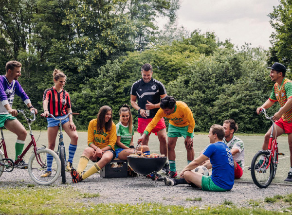 A round thing a group of people dressed in football clothing sitting around a campfire.