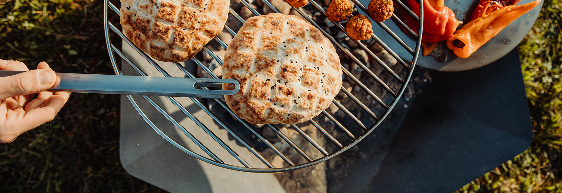 Auf dem Bild ist eine Person zu sehen, die ein Messer über einem Grill hält.