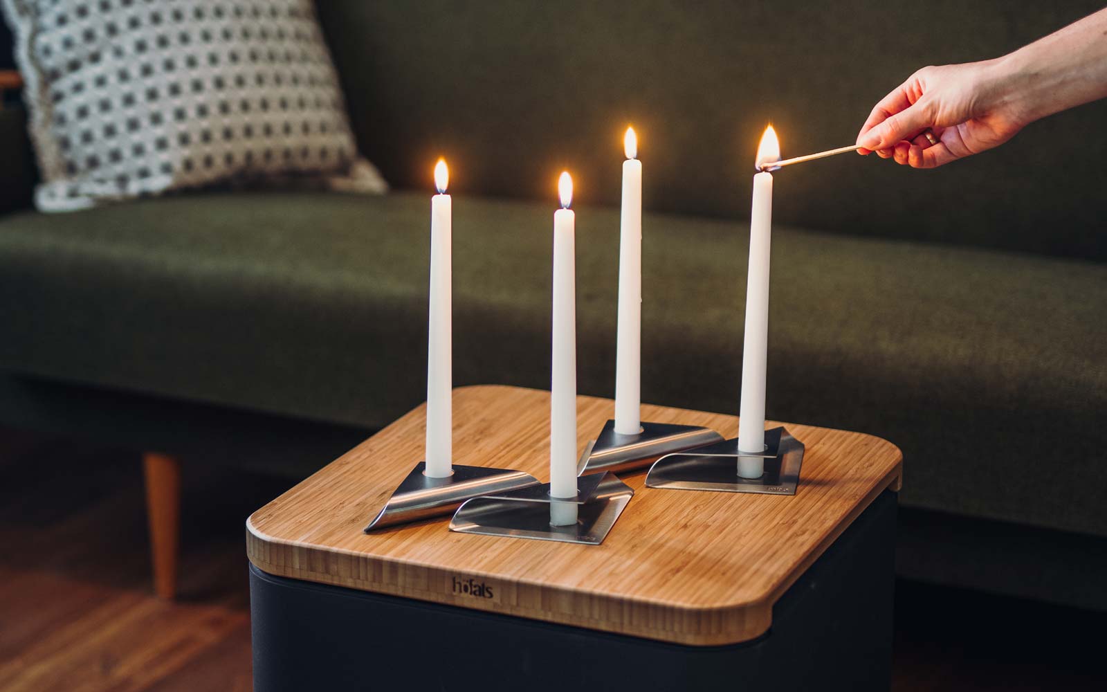 SQUARE CANDLE Bougeoir argent Une vue d'une personne allumant une bougie sur une table, avec la SQUARE CANDLE .