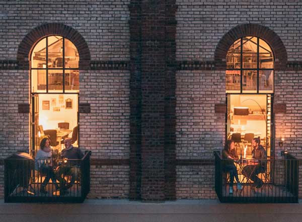 The photo presents people sitting at tables in a restaurant at night, with the CONE.