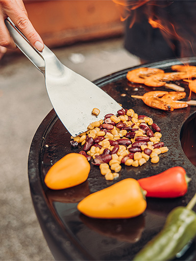 An image showing a person is cooking food on a grill, with the Scraper.