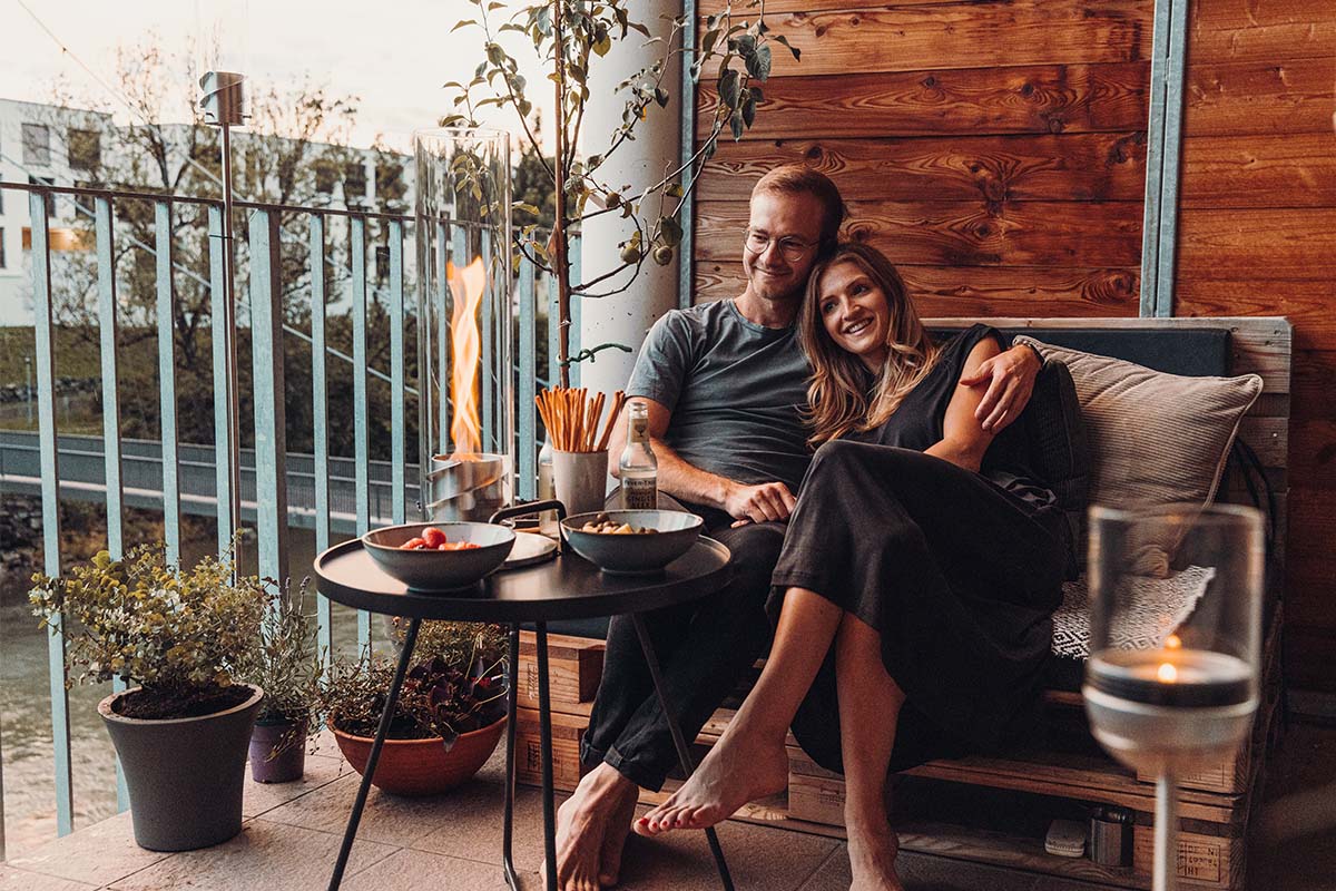SPIN 120 Tabletop Fireplace silver Scene showing a man and woman sitting on a couch with a plate of food, where the Spin 90 Tablefire silver stands out for its practical elegance.