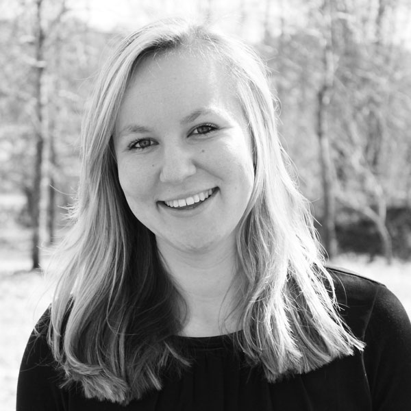 Eine Frau in einem schwarzen Shirt lächelt in die Kamera.