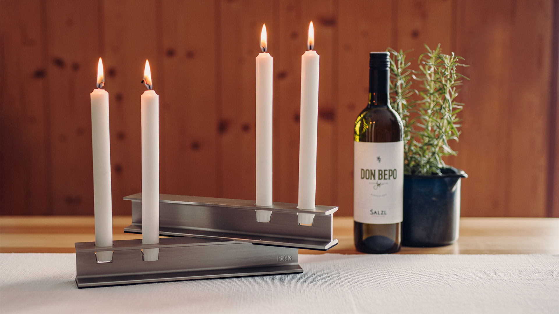 De foto toont een fles wijn en een kaarsenhouder, met de HENRY METAL II Kaarsenhouder in zilver.